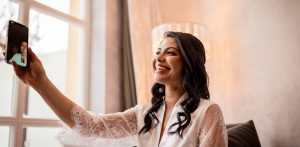 Glückliche Braut beim Getting-Ready im Hotel Adler in Hinterzarten, während sie ihre Familie im Ausland per Videoanruf kontaktiert, fotografiert von Hochzeitsfotografin Isabela Campos.