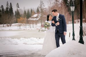 Foto einer Winterhochzeit im Schwarzwald am Parkhotel Adler in Hinterzarten. Das Brautpaar steht bei einer freien Trauung vor einem malerischen Hintergrund aus verschneiten Bäumen und Bergen. Sie schauen sich tief in die Augen und sagen "Ja" zueinander.