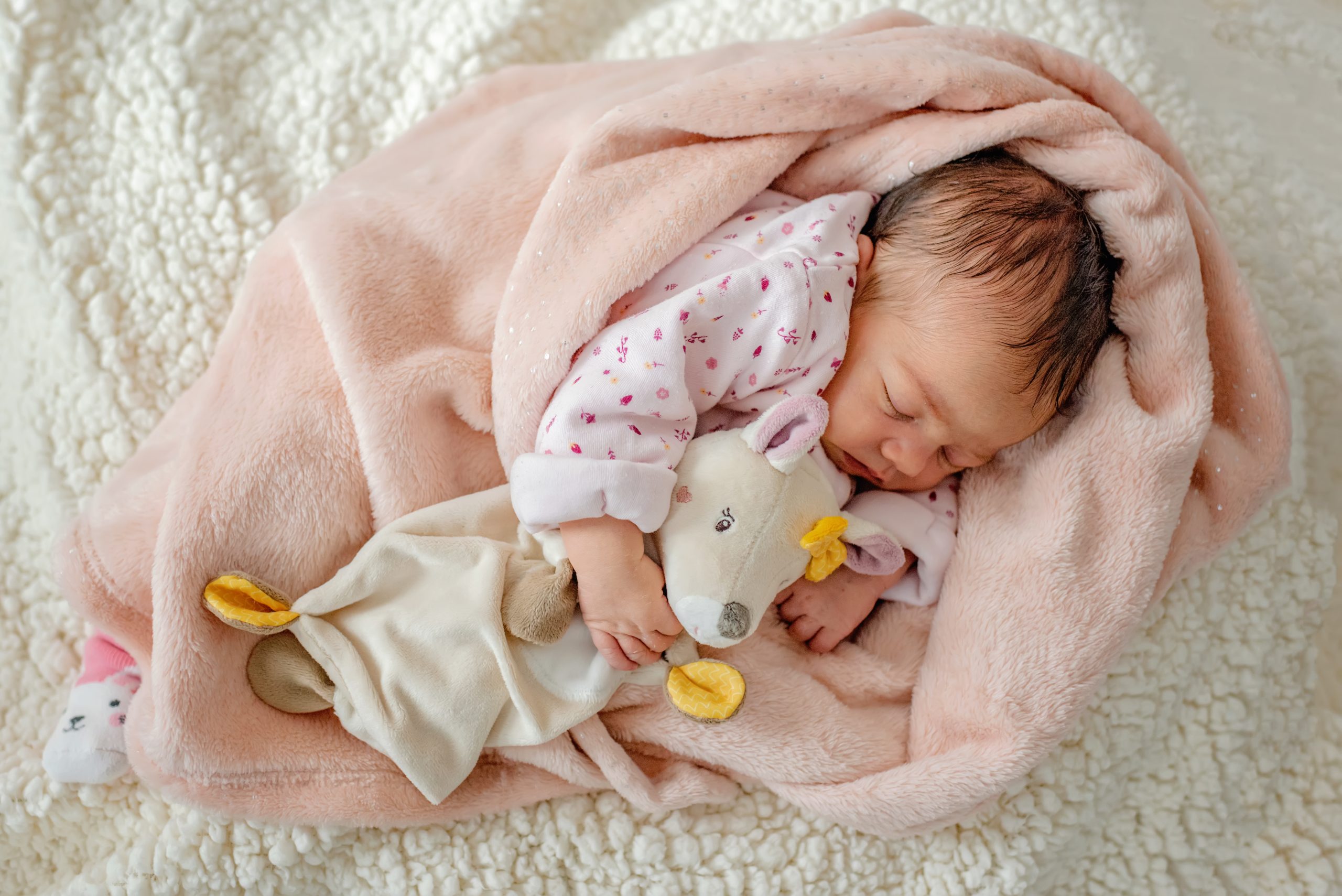 Newborn-Shooting im Wohnzimmer in Durbach, Baby liegt in einer Kiste mit kuscheligen Accessoires