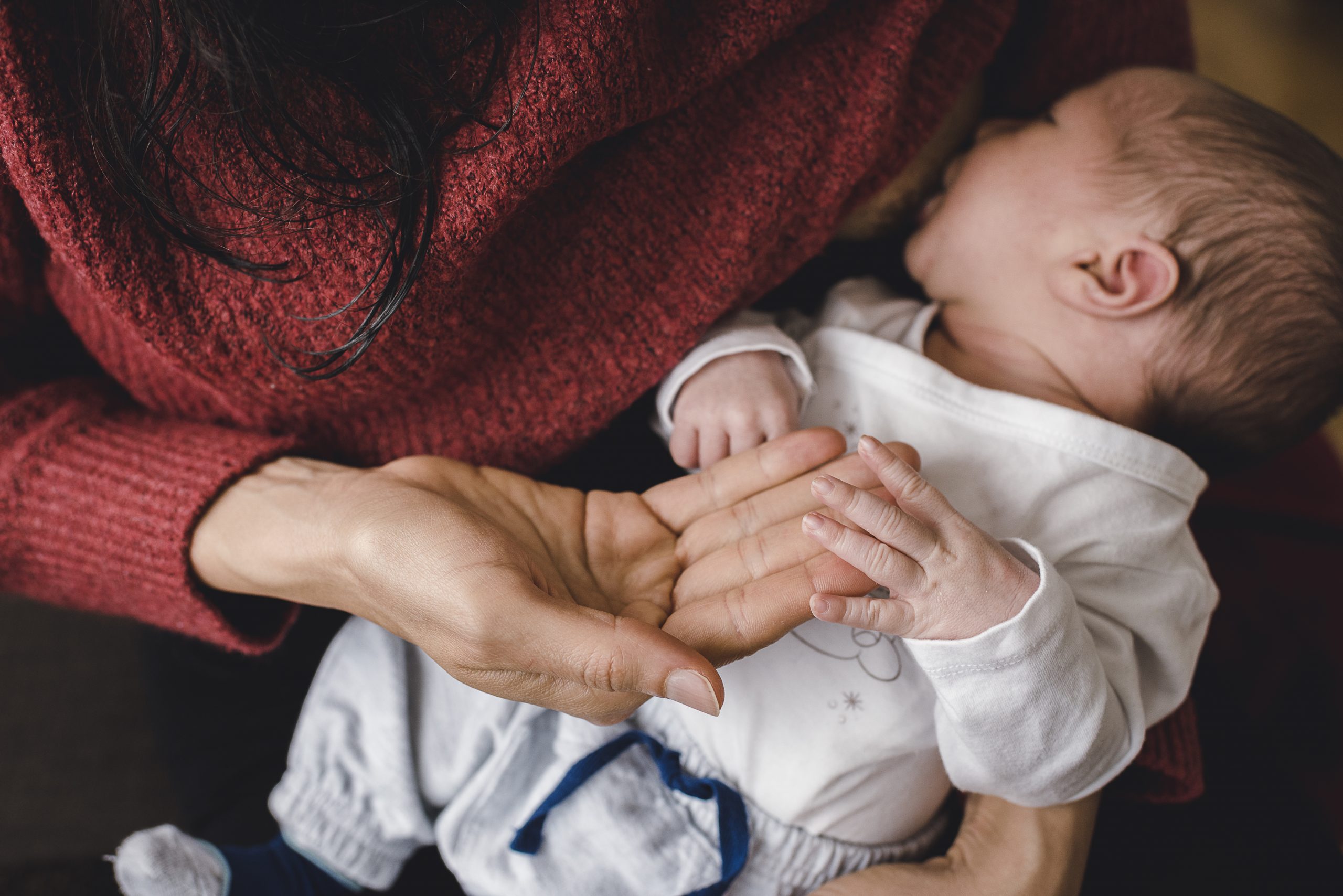 Newborn-Shooting zu Hause in Offenburg, Detailfoto von der Mama, die das Baby während des Stillens hält