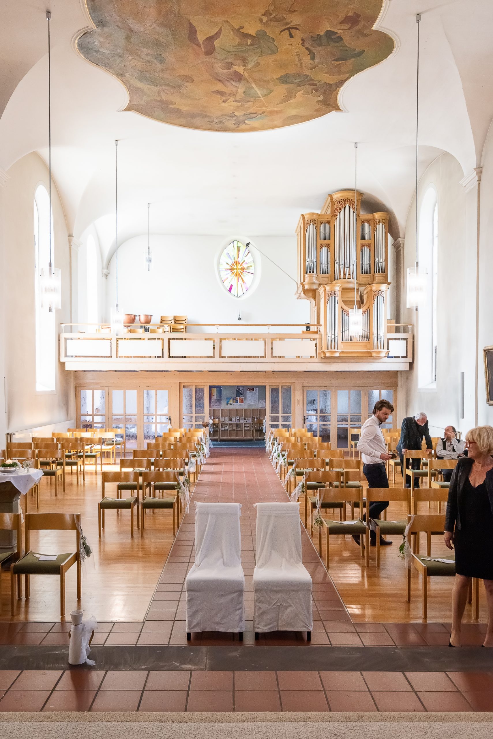 Ein Foto, das die Vorbereitungen für eine kirchliche Hochzeit in der Evangelischen Kirche in Friesenheim zeigt. Das Bild fängt den Innenraum der Kirche ein, der für die Trauungszeremonie geschmückt wurde. Im Hintergrund sind die Kirchenbänke und der Altar zu sehen.