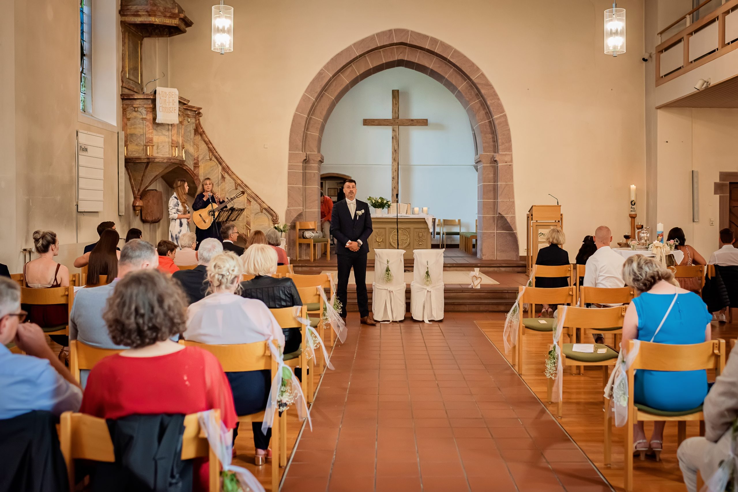 Ein Foto, das den Bräutigam während einer kirchlichen Hochzeit in der Evangelischen Kirche in Friesenheim zeigt. Der Bräutigam wartet am Altar auf seine Braut, während die Gäste bereits ihre Plätze eingenommen haben.