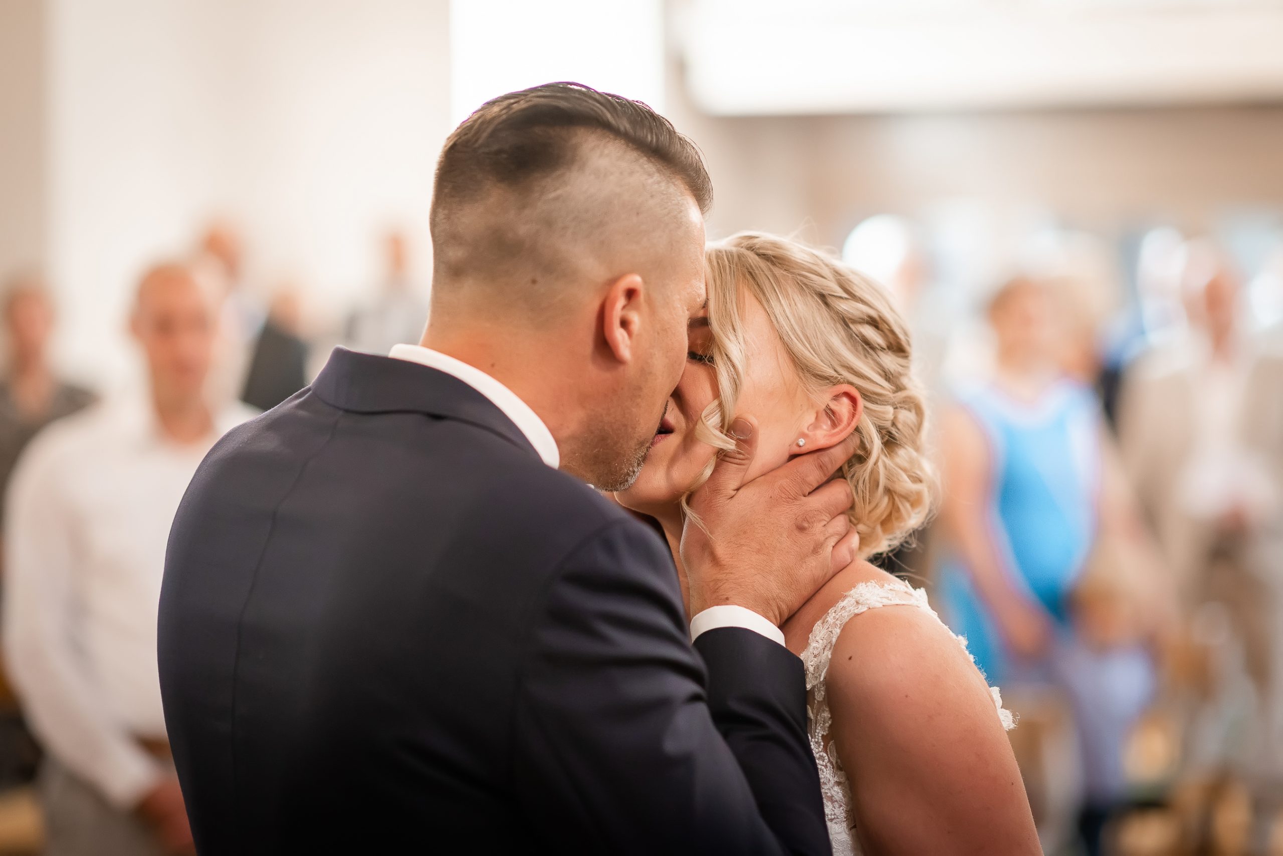 Ein Foto, das einen Nahaufnahme des romantischen Moments zeigt, als der Bräutigam seine Braut am Altar küsst. Das Bild fängt das Detail der Geste ein, die die Emotionen und die Liebe des Paares zeigt.