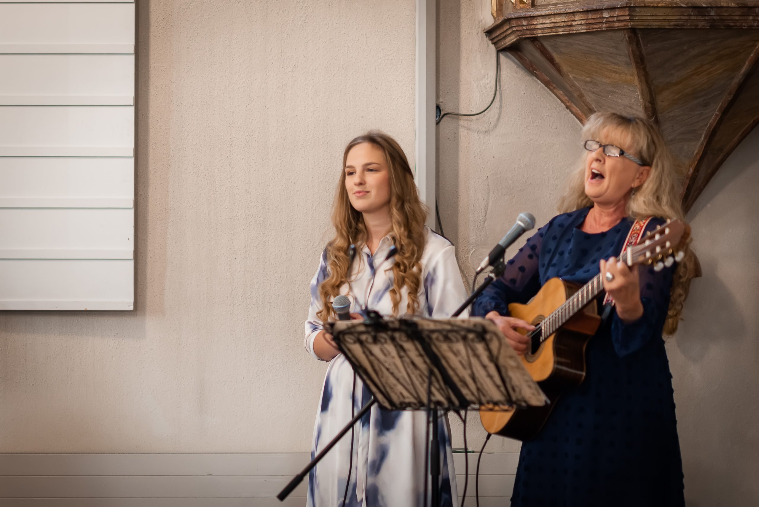 Ein Foto, das die Sängerin Ulla Christ und ihre Tochter Lisa-Marie Christ während einer kirchlichen Hochzeit in der Evangelischen Kirche in Friesenheim zeigt. Die beiden singen zusammen und tragen zur feierlichen Atmosphäre der Zeremonie bei.