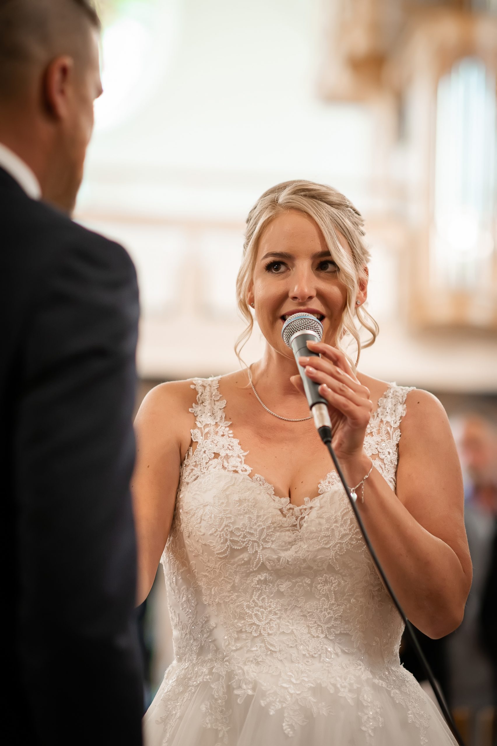 Ein Foto, das den aufregenden Moment zeigt, als die Braut während einer kirchlichen Hochzeit in Friesenheim das Mikrofon übernimmt und mit einem Auftritt den Bräutigam überrascht.