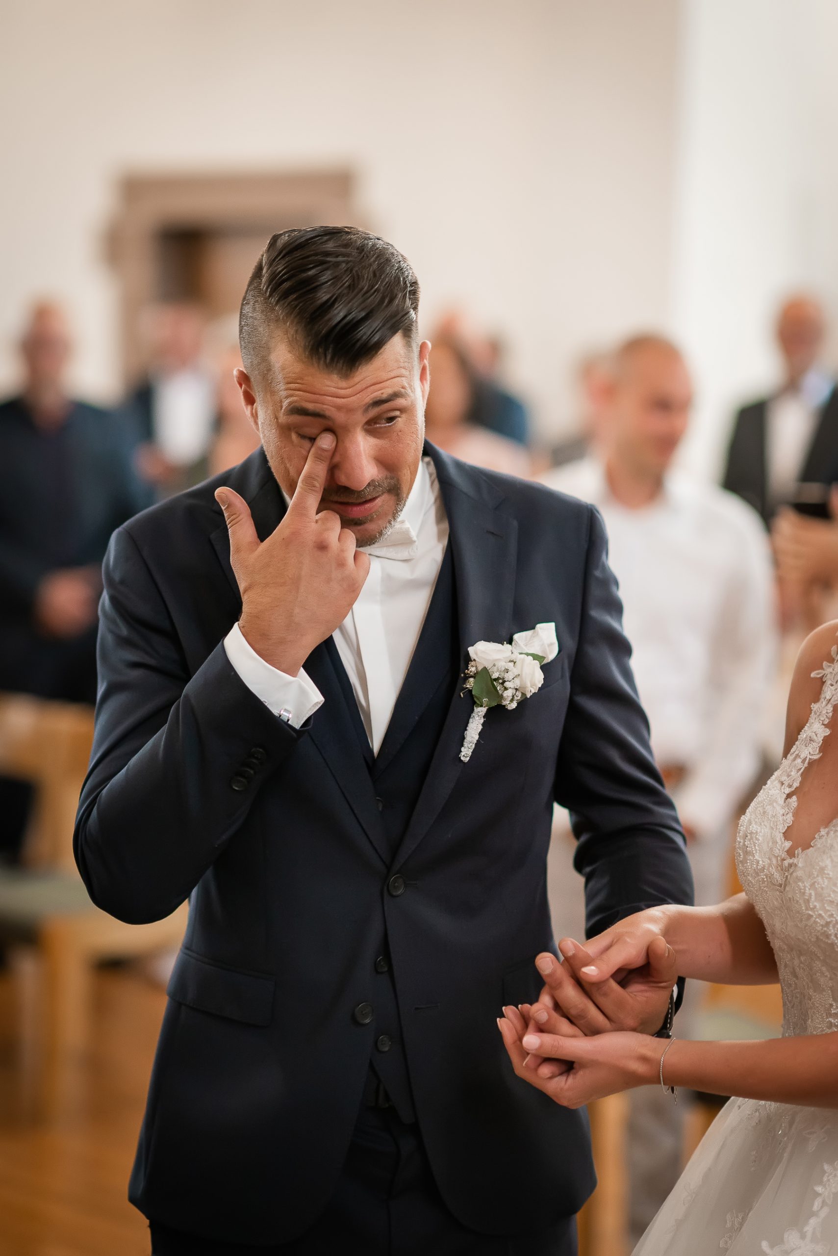 Ein Foto, das die emotionale Reaktion des Bräutigams zeigt, als er von seiner Braut während einer kirchlichen Hochzeit in Friesenheim überrascht wird.