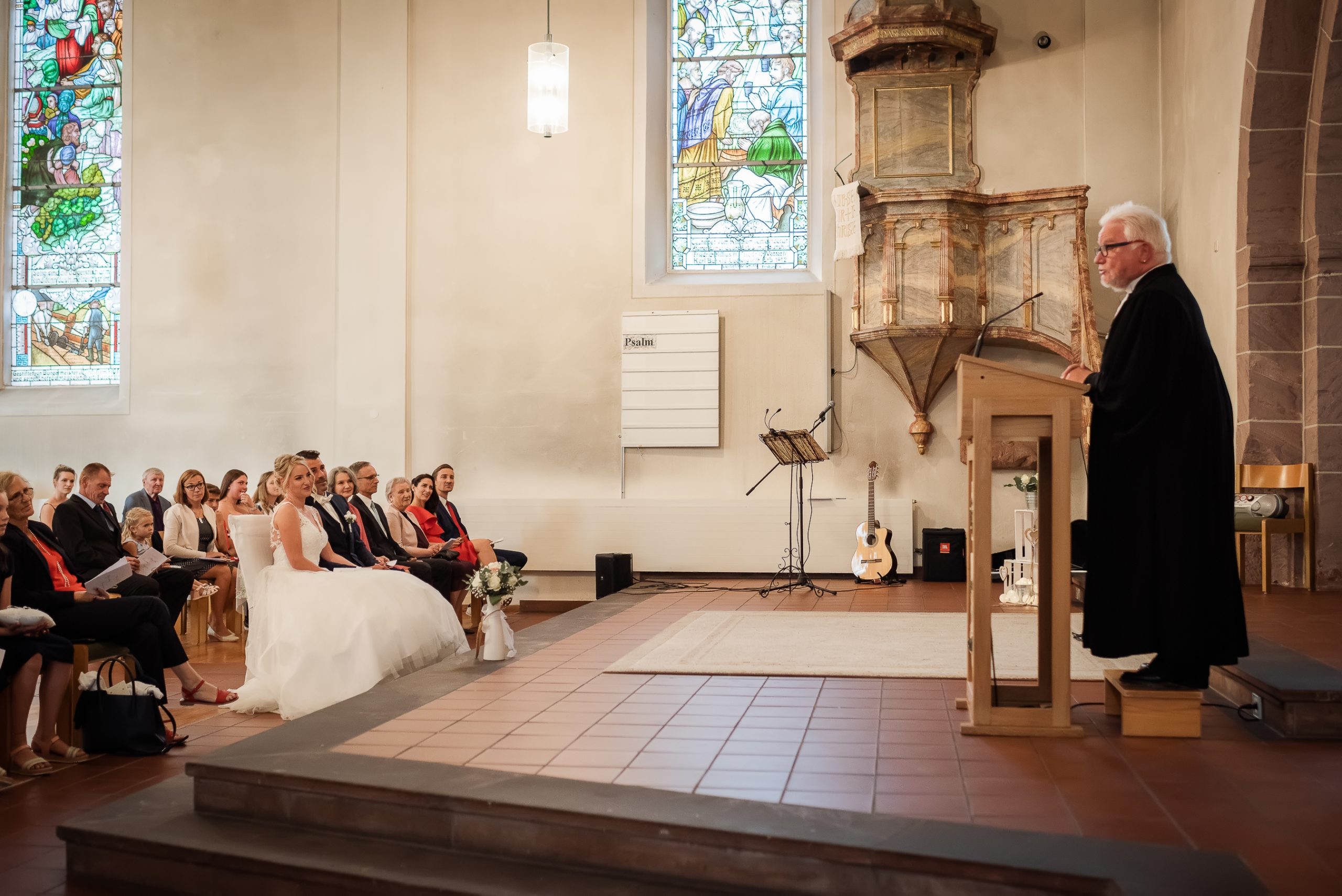Ein Foto des Pfarrers, der in der Evangelischen Kirche in Friesenheim die Trauung leitet, während das Brautpaar und die Hochzeitsgäste zuhören.