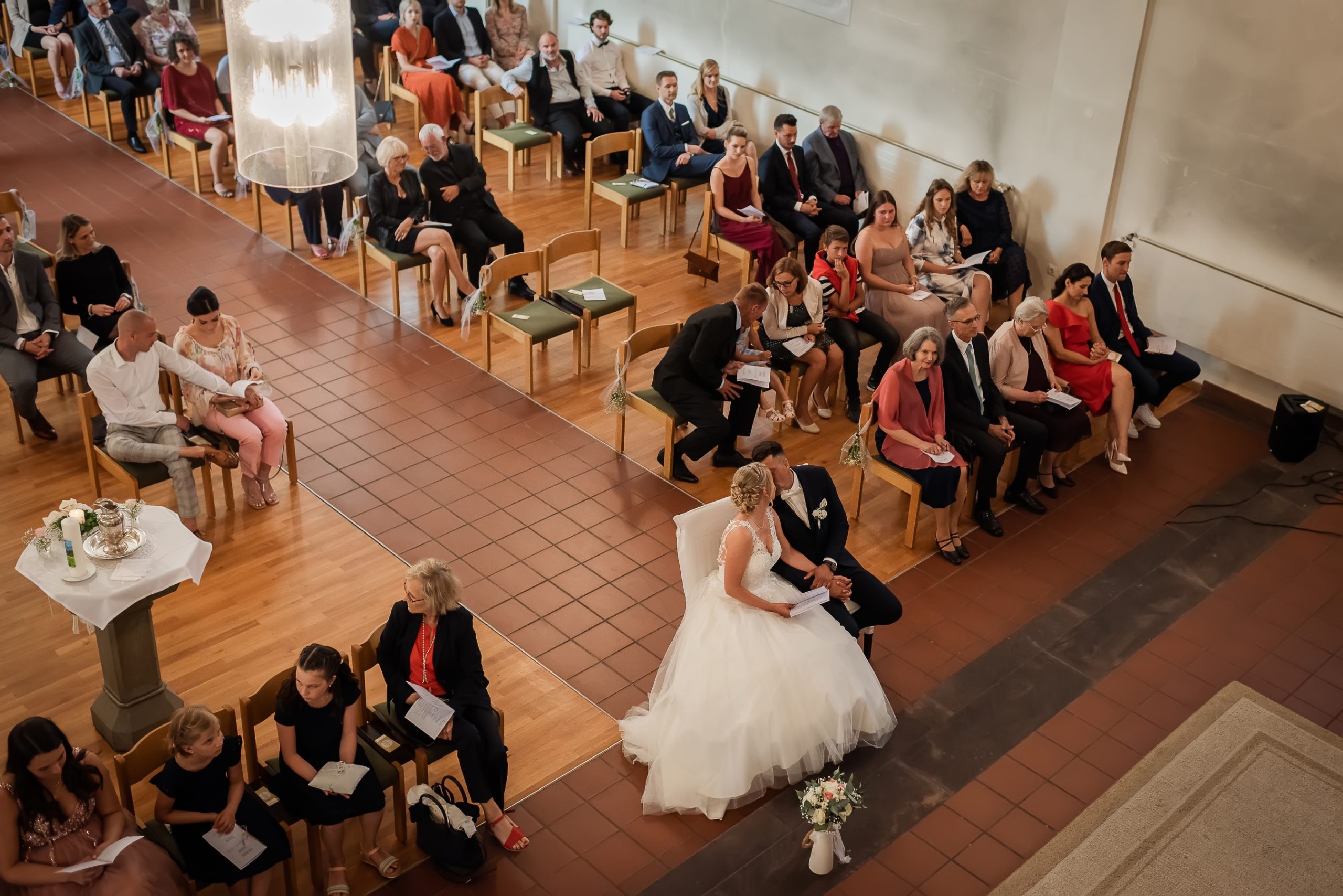Ein Foto aus der Vogelperspektive einer Hochzeit in der Evangelischen Kirche in Friesenheim. Das Brautpaar und seine Gäste sind während der kirchlichen Trauung zu sehen.
