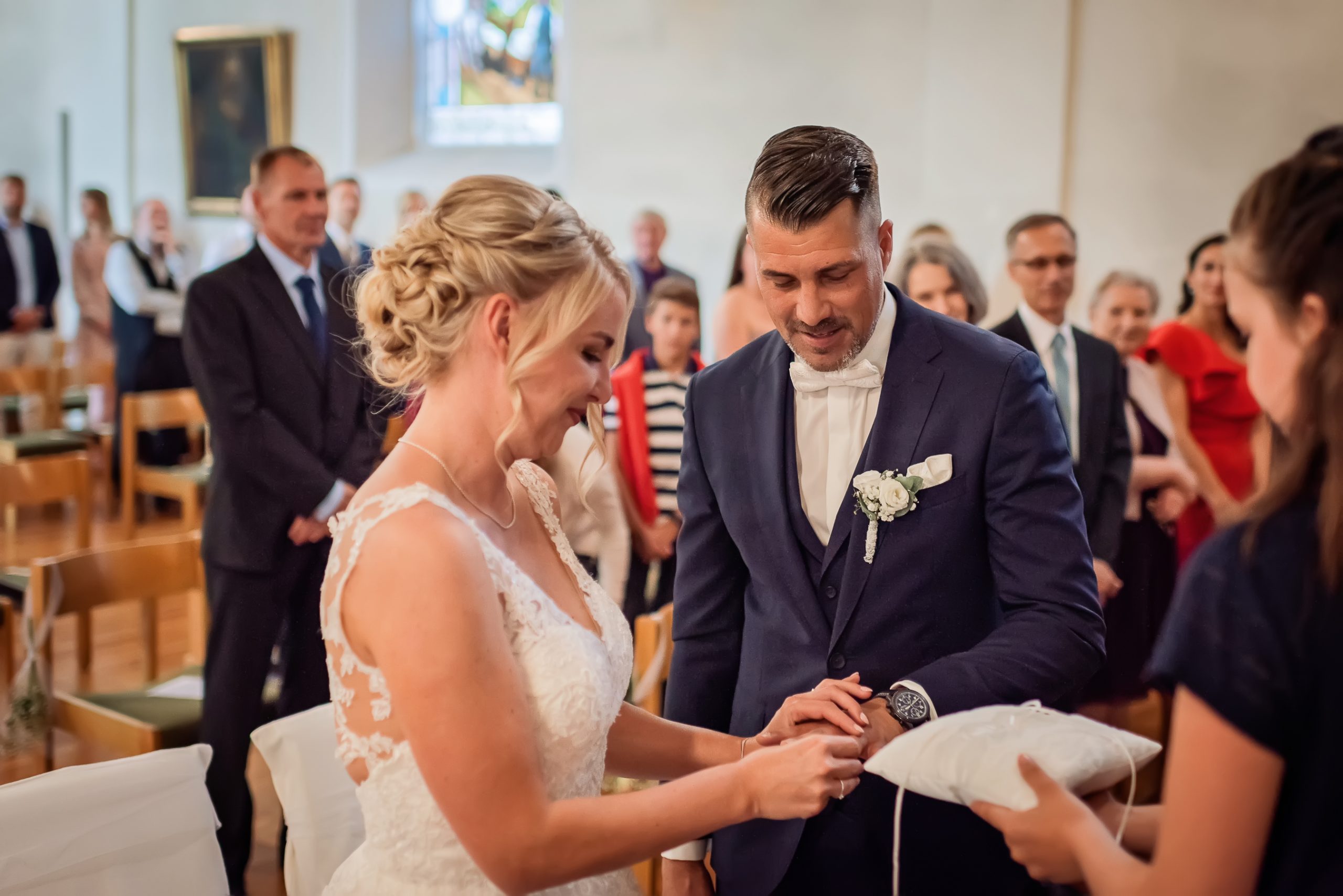 Foto von der Ringtausch-Zeremonie in einer Kirche in Friesenheim. Die Hände des Brautpaars sind zu sehen, während die Braut den Ring auf den Finger des Bräutigams setzt.