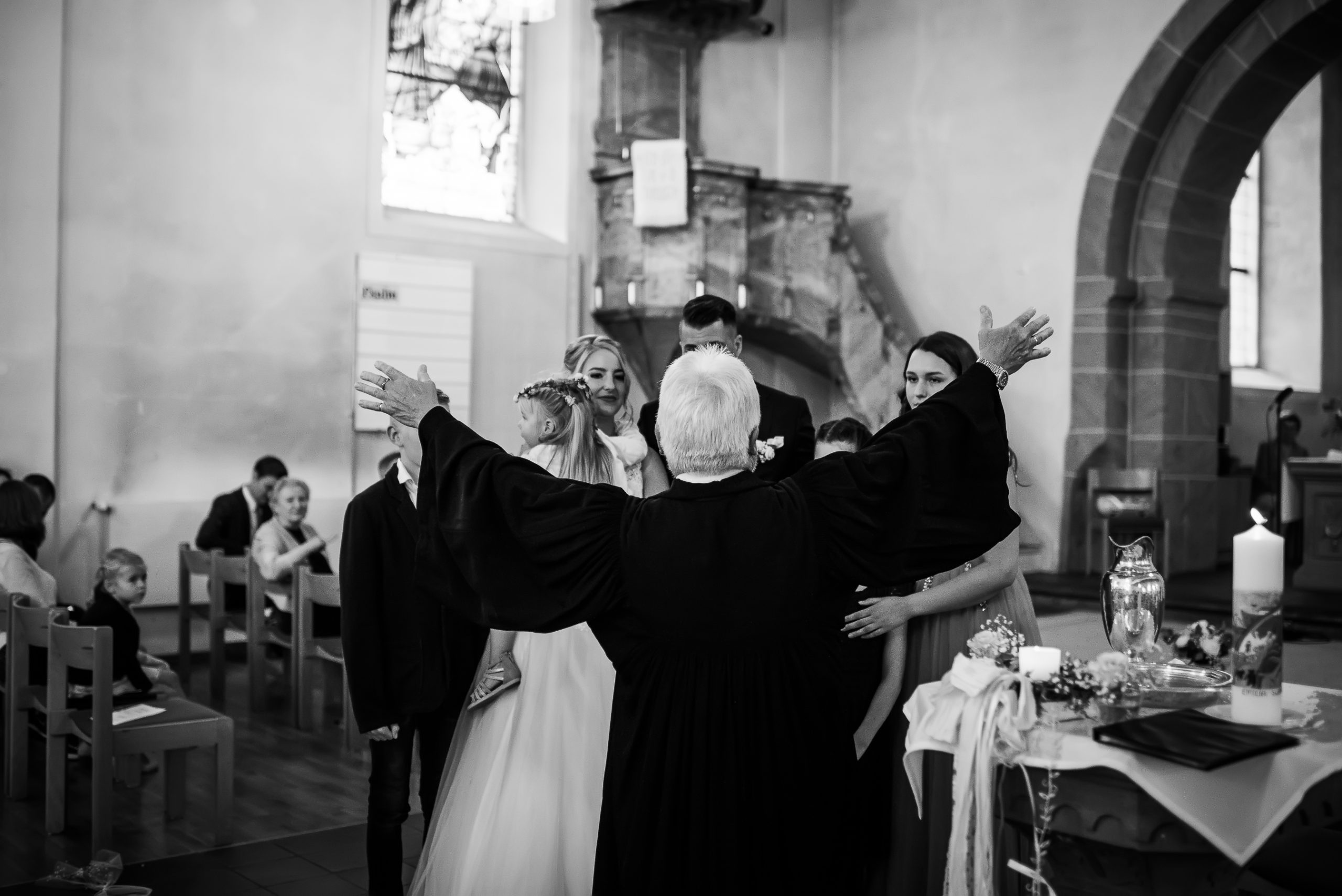 Foto von einer Taufe bei einer Hochzeit in Friesenheim, bei der das Brautpaar und alle Kinder anwesend sind und der Pfarrer die Familie segnet.