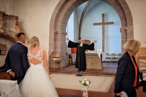 Ein Brautpaar und der Pfarrer bei Ende der Hochzeitszeremonie in der Kirche in Friesenheim.