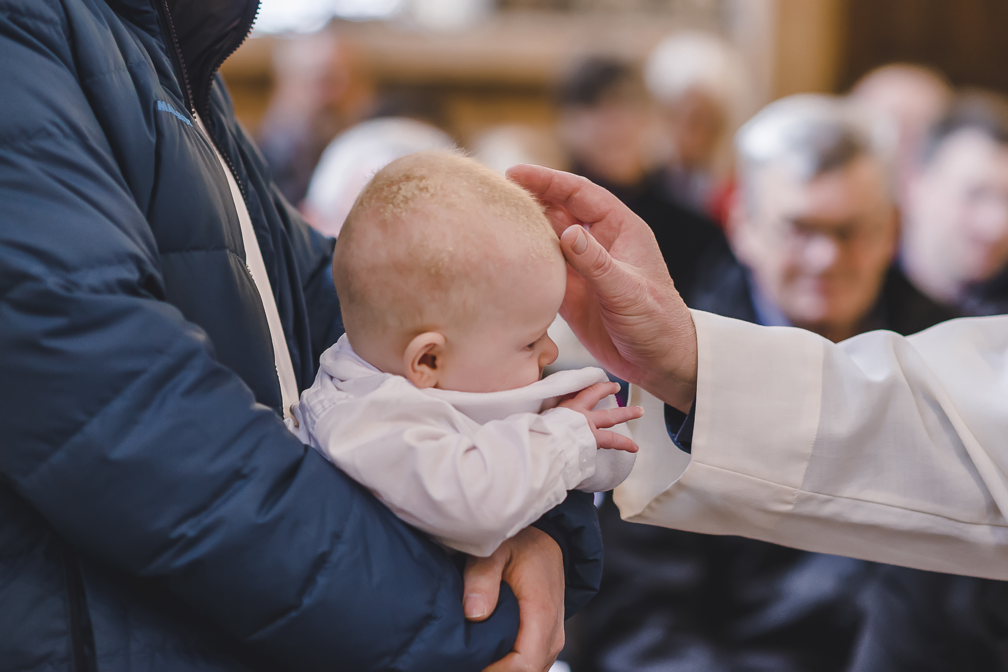 Eine Detailaufnahme von der Segnung eines Kindes während einer Taufzeremonie. Tauffotografin Isabela Campos in Offenburg.