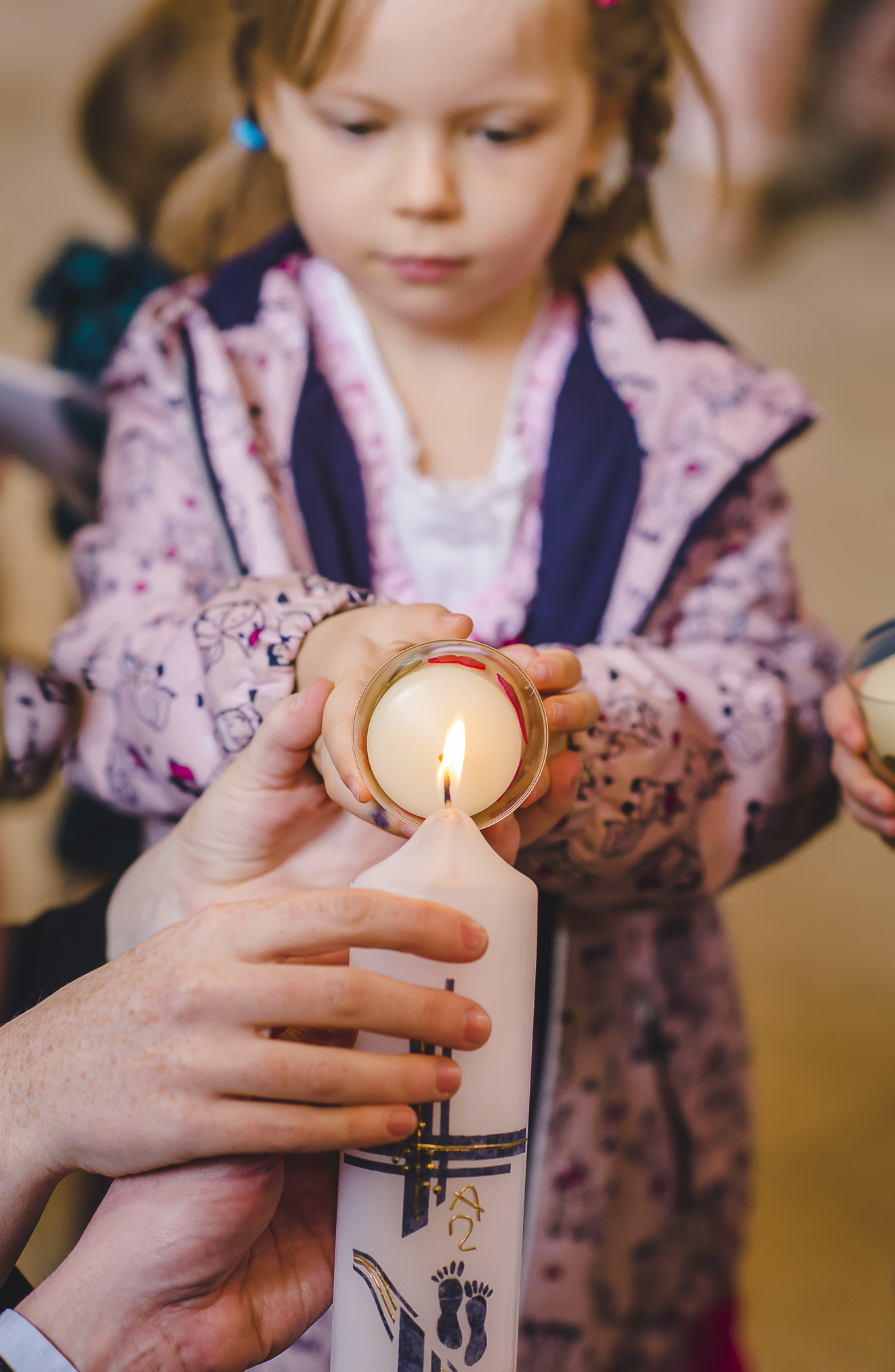 Eine Nahaufnahme einer Taufkerze, die von einem Kind während einer Taufzeremonie in der Kapelle des Europa-Parks angezündet wird.