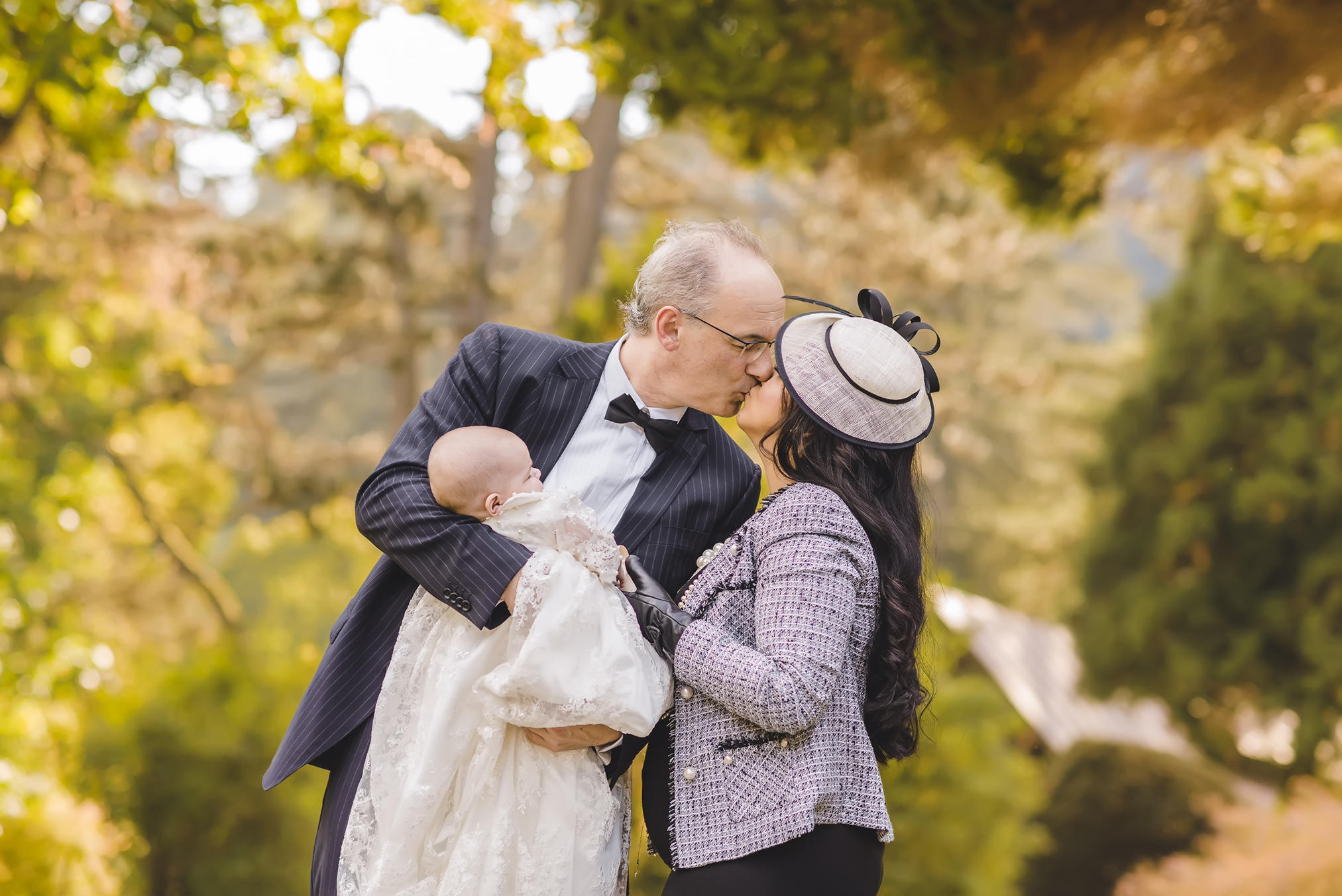 Ein Foto einer Familie mit Baby nach einer Taufzeremonie in Bad Wildbad. Das Baby trägt ein traditionelles weißes Taufkleid und posiert mit Mama und Papa für ein Familien-Shooting.