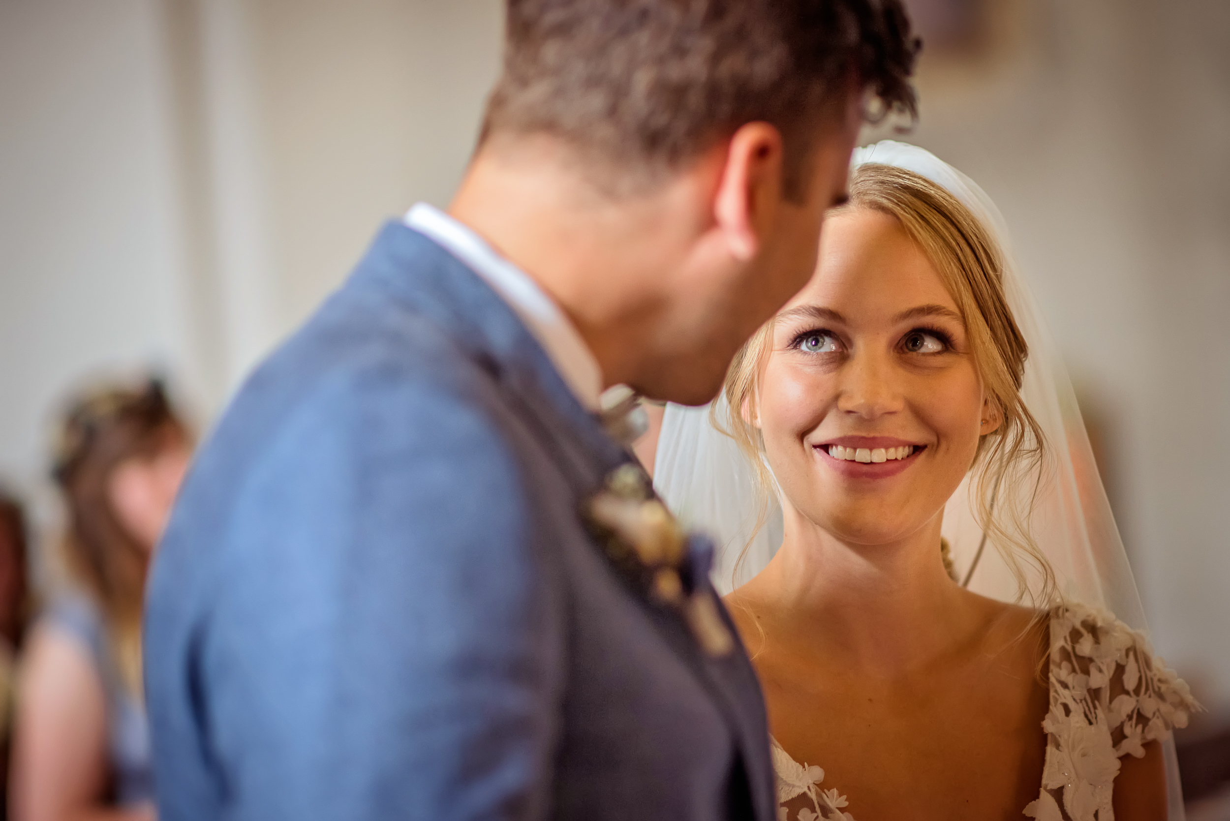 Portraitfotografie der Braut mit Fokus auf dem Wort "Ja", das sie ausgesprochen hat, während sie lacht und ihren Bräutigam mit großen grünen Augen liebevoll ansieht.