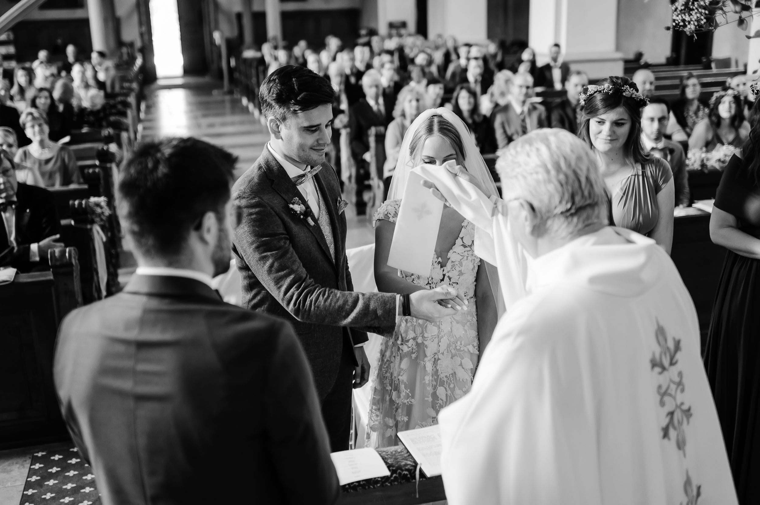 Brautpaar im Altar während einer kirchlichen Trauung, Pater Roman segnet ihre Hände.