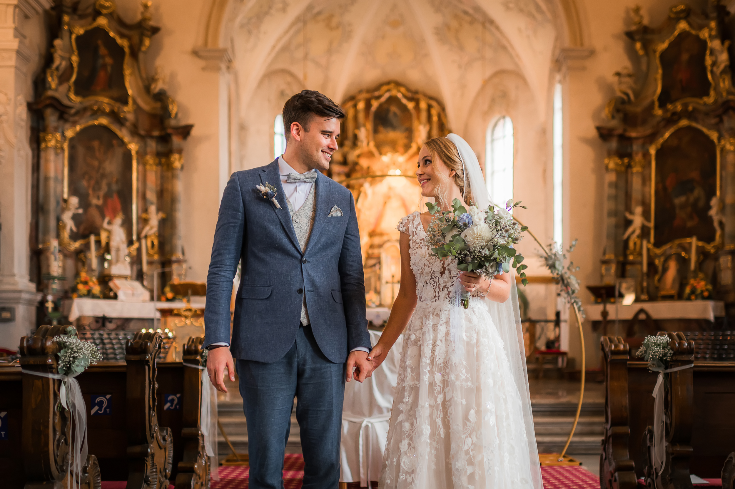 Brautpaar verlässt den Altar der Wallfahrtskirche Todtmoos nach der kirchlichen Trauung und schaut glücklich in die Kamera.