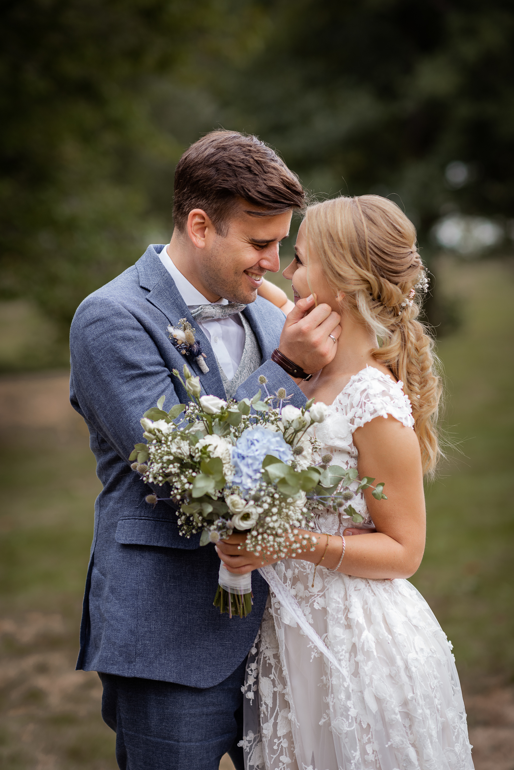 rautpaar Fotoshooting in Todtmoos im Schwarzwald. Braut hält einen Blumenstrauß im Boho-Stil in der Hand, während sie und der Bräutigam sich liebevoll umarmen und tief in die Augen schauen.