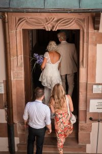 Ein Brautpaar läuft Hand in Hand durch einen eleganten Korridor im alten Rathaus in Freiburg
