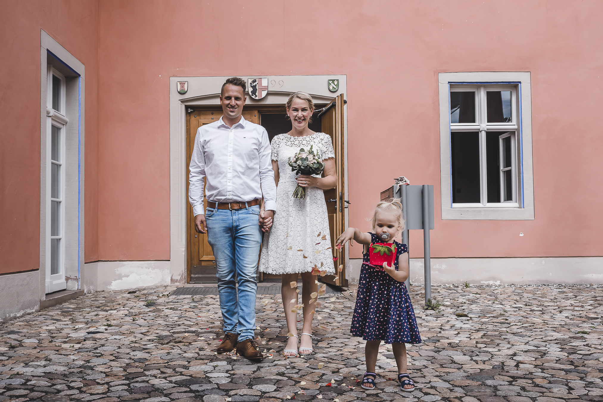 Das Brautpaar verlässt das Standesamt in Kirchzarten und wird von der Tochter mit Rosenblättern beschenkt. Hochzeitsfotografin Isabela Campos hält diesen wunderbaren Augenblick für die Ewigkeit fest.