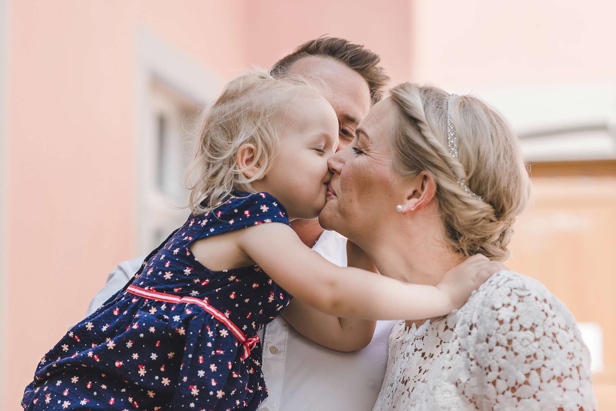 Papa hält Kind, während Tochter Mama küsst, intime Standesamt-Hochzeit in Kirchzarten, Fotografin Isabela Campos
