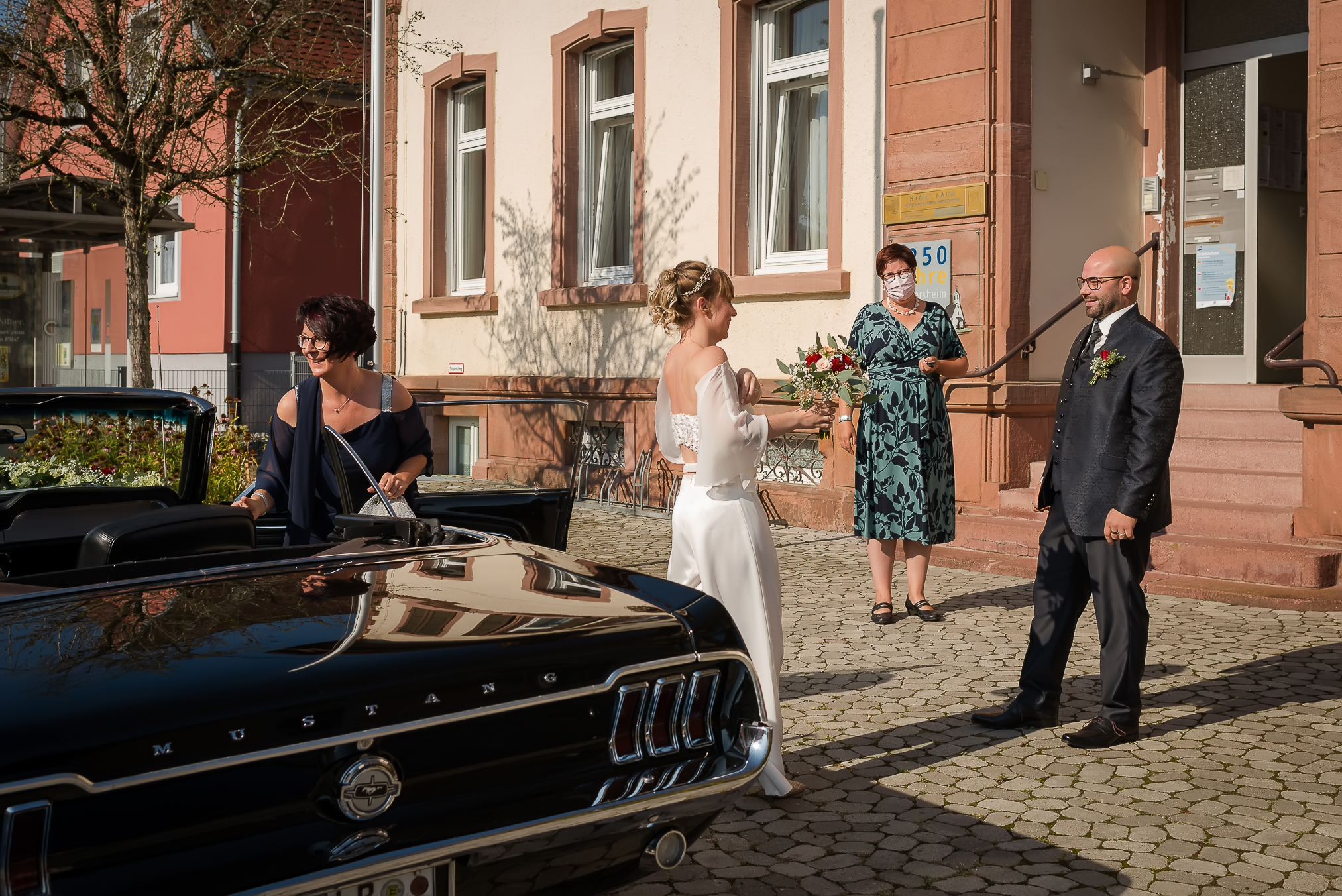 Eine Braut steigt aus einem Oldtimer vor dem Rathaus in Mietersheim für ihre standesamtliche Trauung aus.