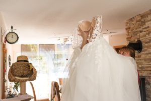 Die Braut wird von ihrer besten Freundin geholfen, während sie ihr Hochzeitskleid in Lahr anzieht.