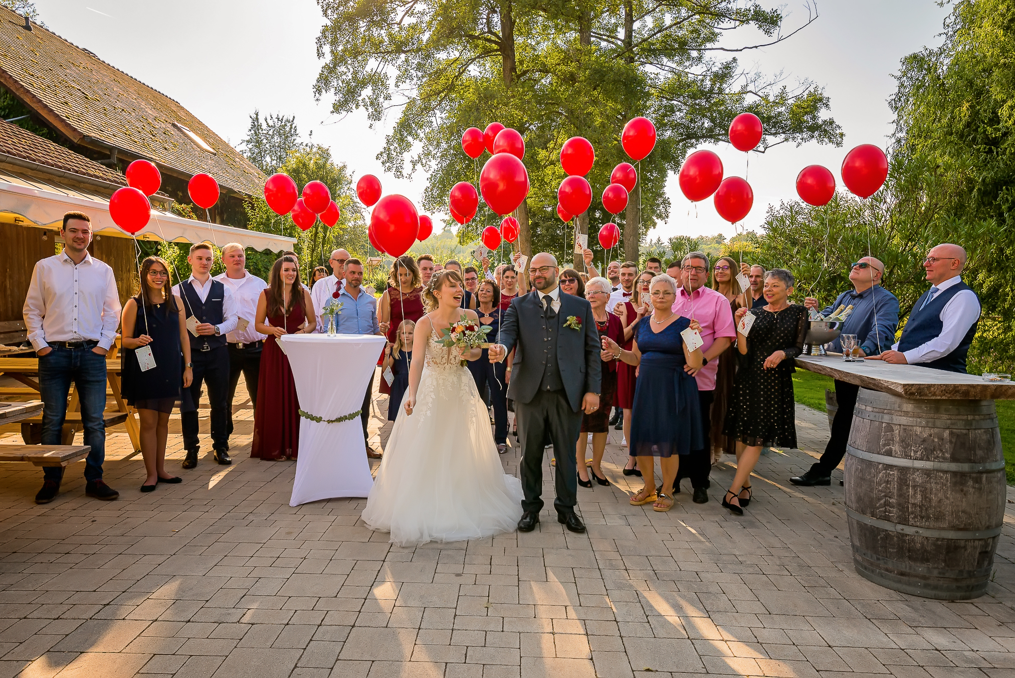 Hochzeit im Haus am Teich in Ettenheim - Familie und Gäste lassen rote Luftballons aufsteigen vor dem Haus