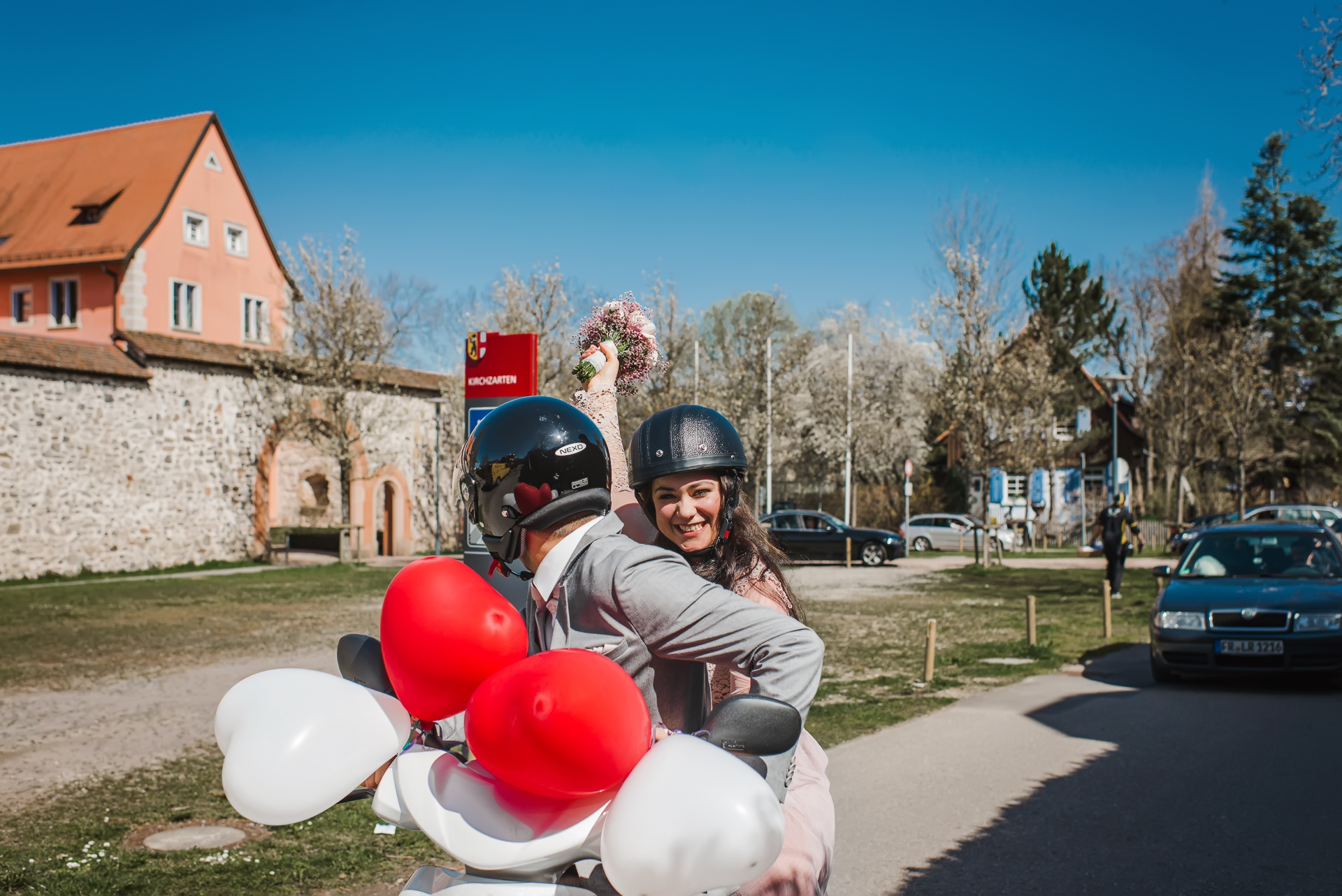 Brautpaar verlässt die Talvogtei in Kirchzarten auf einem Motorrad, die Braut hält den Blumenstrauß und lächelt in die Kamera