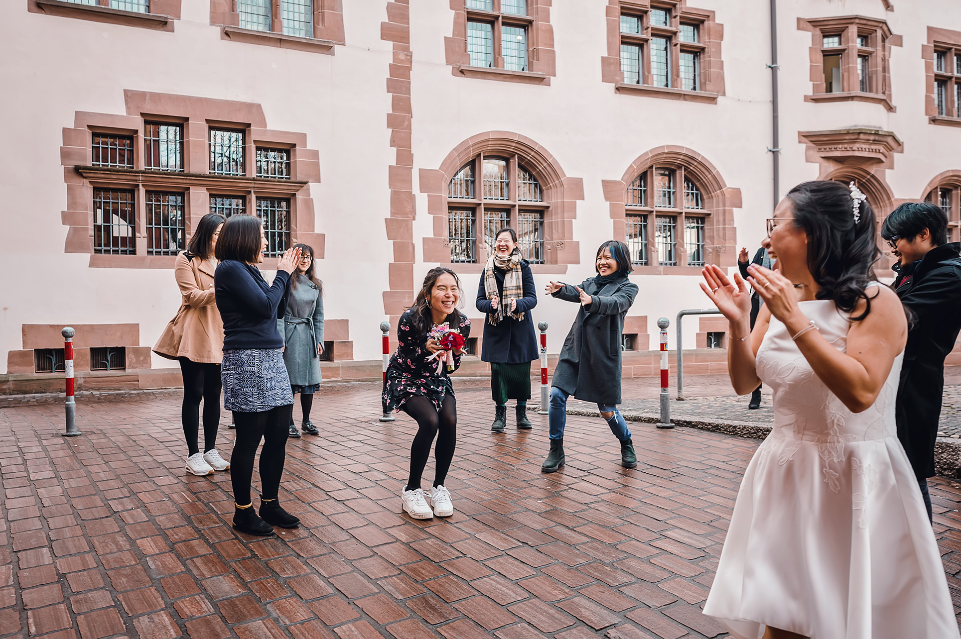 Ein Foto von Freunden, die den Brautstrauß während einer standesamtlichen Trauung in Freiburg fangen. Die Freunde halten die Blumen fest und lachen vor Glück.
